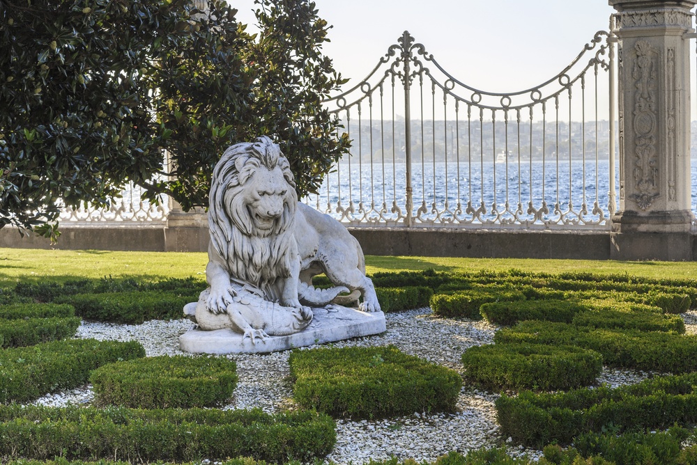 Another angle of the Dolmabahçe Palace lion statue, showing the fine detail of the marble carving and the statue's position within the formal palace garden setting